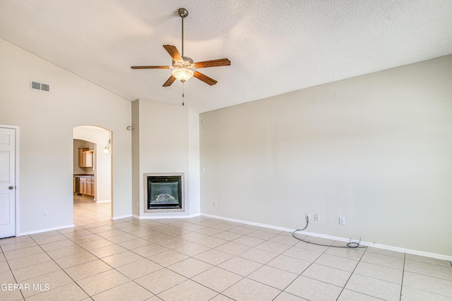 11361 Charles Reynolds Ln, El Paso, TX 79934 - unfurnished living room with ceiling fan, arched walkways, light tile patterned floors, a glass covered fireplace, and a textured ceiling