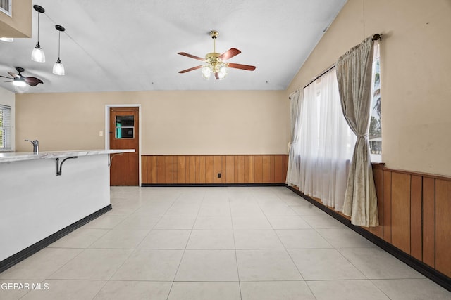 9913 Bomarc St, El Paso, TX 79924 - empty room featuring ceiling fan, wainscoting, wooden walls, a sink, and lofted ceiling
