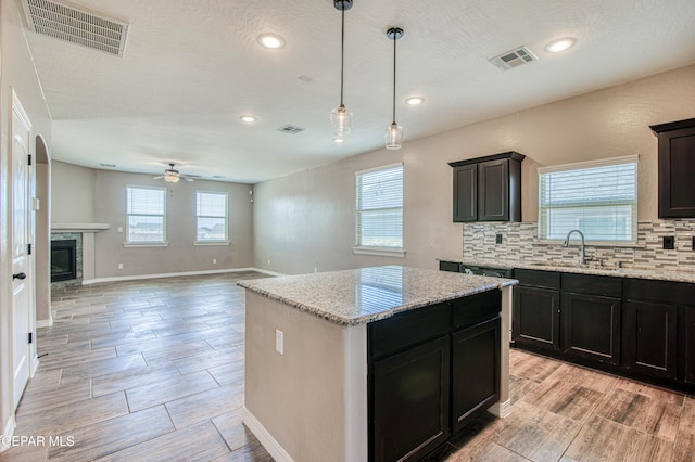 12772 Silver Streak Ave, El Paso, TX 79928 - kitchen with a sink, a ceiling fan, a kitchen island, backsplash, and wood tiled floors