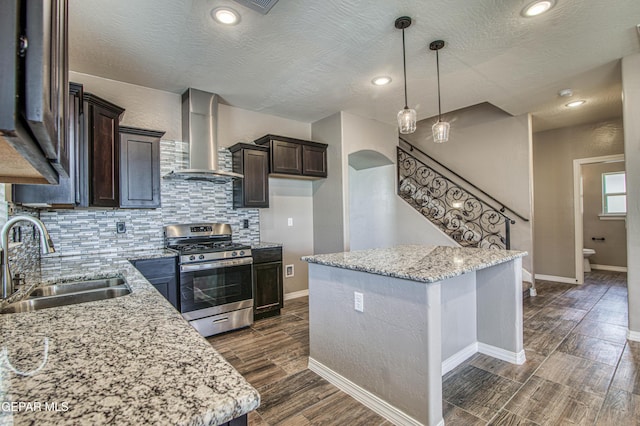 12772 Silver Streak Ave, El Paso, TX 79928 - kitchen featuring stainless steel gas range, a sink, wall chimney range hood, dark brown cabinets, and dark wood-style floors