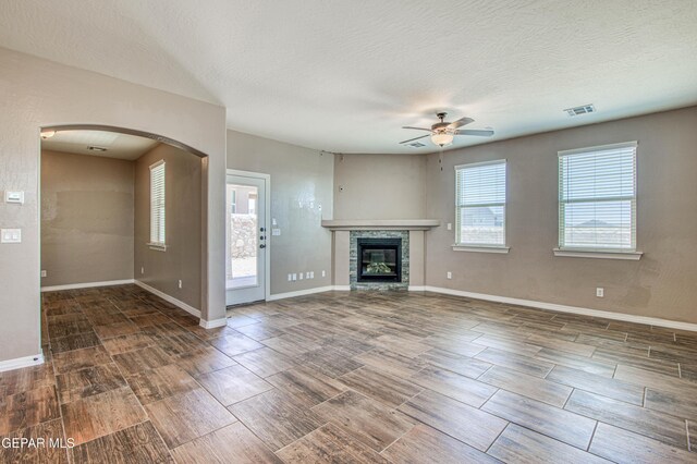 12772 Silver Streak Ave, El Paso, TX 79928 - unfurnished living room with a ceiling fan, wood finish floors, arched walkways, a glass covered fireplace, and baseboards