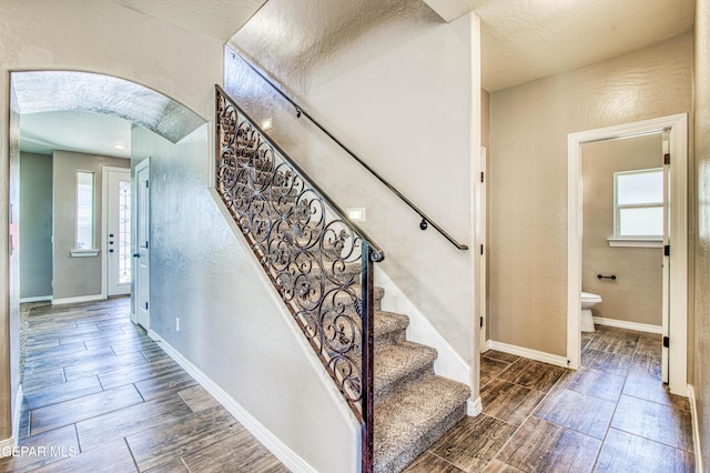 12772 Silver Streak Ave, El Paso, TX 79928 - stairway featuring wood finish floors, healthy amount of natural light, arched walkways, baseboards, and a textured wall