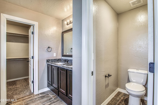 12772 Silver Streak Ave, El Paso, TX 79928 - bathroom featuring wood tiled floors, vanity, toilet, a textured wall, and baseboards