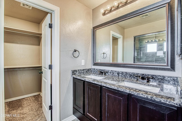 12772 Silver Streak Ave, El Paso, TX 79928 - full bathroom featuring double vanity, a textured wall, a spacious closet, and baseboards
