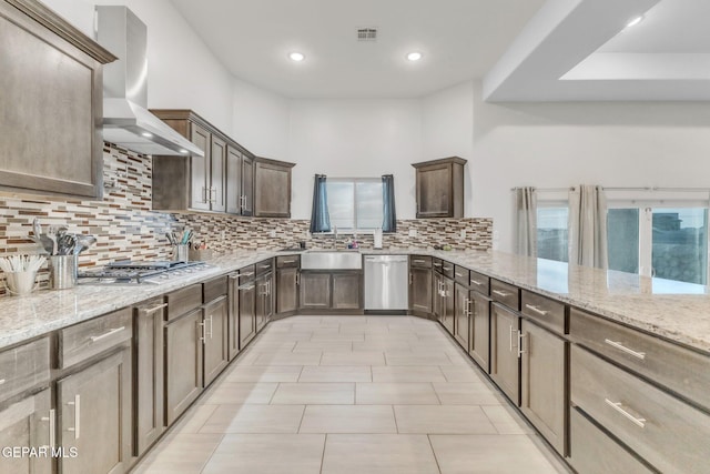 2367 Enchanted Peaks Ln, El Paso, TX 79911 - kitchen with wall chimney range hood, stainless steel appliances, a sink, decorative backsplash, and light stone counters