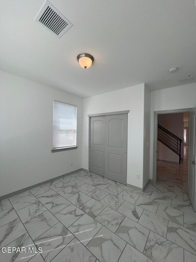 12868 Star Gaze Ave, El Paso, TX 79928 - unfurnished bedroom featuring baseboards, a closet, and light marble finish floors