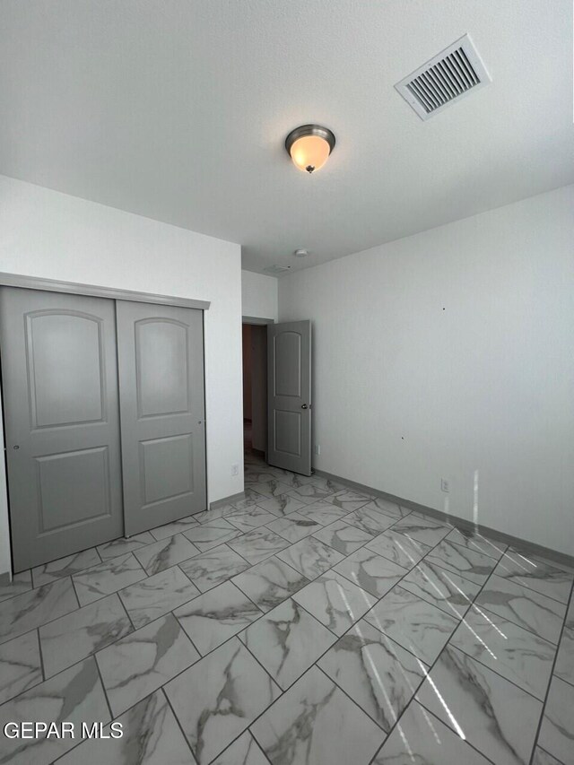 12868 Star Gaze Ave, El Paso, TX 79928 - unfurnished bedroom featuring light marble finish flooring, a closet, and baseboards