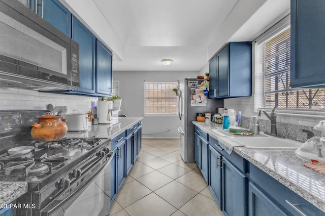 5717 Port Lavaca Dr, El Paso, TX 79924 - kitchen featuring gas stove, black microwave, blue cabinetry, a sink, and decorative backsplash