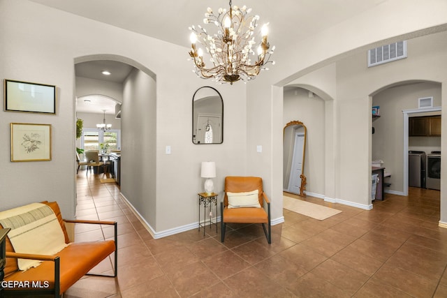 14382 Karen Point Ct, El Paso, TX 79938 - corridor with arched walkways, a chandelier, washer and clothes dryer, tile patterned floors, and baseboards