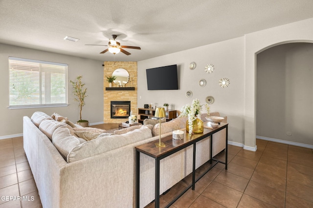 14382 Karen Point Ct, El Paso, TX 79938 - living area featuring arched walkways, tile patterned floors, ceiling fan, a large fireplace, and baseboards
