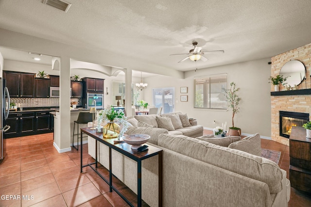 14382 Karen Point Ct, El Paso, TX 79938 - living area featuring a ceiling fan, a fireplace, a chandelier, light tile patterned floors, and a textured ceiling