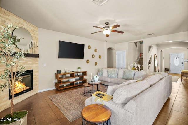 14382 Karen Point Ct, El Paso, TX 79938 - living room with arched walkways, tile patterned floors, a ceiling fan, a fireplace, and baseboards