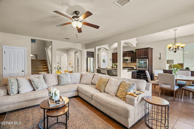 14382 Karen Point Ct, El Paso, TX 79938 - living room with arched walkways, ceiling fan, a chandelier, stairway, and light tile patterned flooring