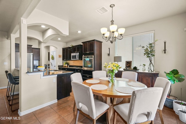 14382 Karen Point Ct, El Paso, TX 79938 - tiled dining area with a chandelier, a sink, arched walkways, recessed lighting, and baseboards