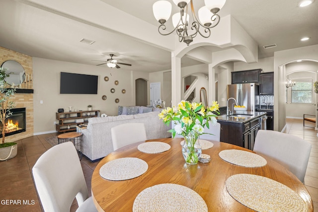 14382 Karen Point Ct, El Paso, TX 79938 - tiled dining area with a chandelier, a sink, a tiled fireplace, arched walkways, and recessed lighting