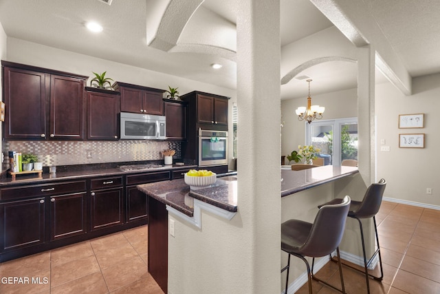 14382 Karen Point Ct, El Paso, TX 79938 - kitchen featuring stainless steel appliances, arched walkways, a breakfast bar area, and light tile patterned floors