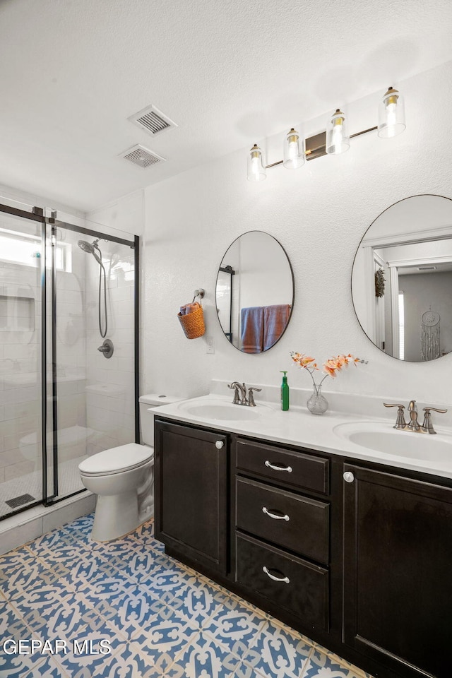 14382 Karen Point Ct, El Paso, TX 79938 - bathroom featuring double vanity, toilet, a stall shower, and a textured ceiling