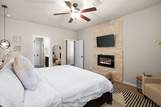 14382 Karen Point Ct, El Paso, TX 79938 - carpeted bedroom featuring a stone fireplace, connected bathroom, baseboards, and a ceiling fan