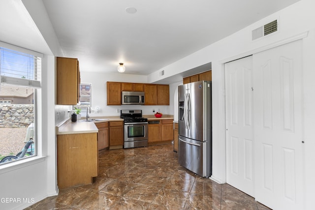 1497 Dunlin Pl, El Paso, TX 79928 - kitchen featuring appliances with stainless steel finishes, brown cabinets, light countertops, and dark marble finish flooring