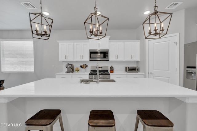 13727 Harbottle St, El Paso, TX 79928 - kitchen with a chandelier, appliances with stainless steel finishes, a sink, a large island, and white cabinets