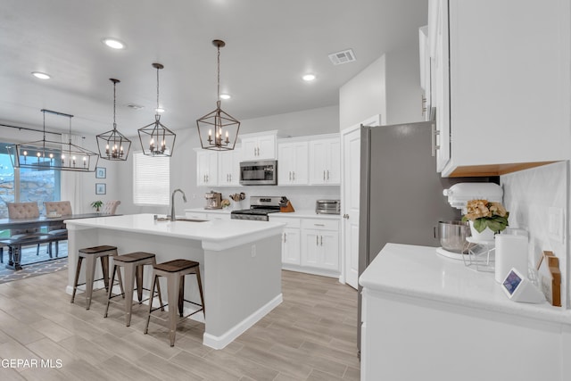 13727 Harbottle St, El Paso, TX 79928 - kitchen with appliances with stainless steel finishes, a chandelier, a kitchen breakfast bar, a center island with sink, and light countertops