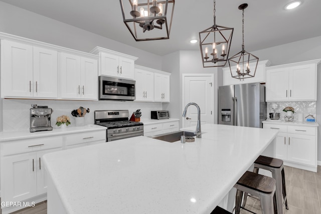 13727 Harbottle St, El Paso, TX 79928 - kitchen featuring appliances with stainless steel finishes, a chandelier, a sink, backsplash, and an island with sink