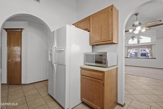 4513 Gen Maloney Cir, El Paso, TX 79924 - kitchen featuring stainless steel microwave, ceiling fan, white refrigerator with ice dispenser, arched walkways, and light countertops