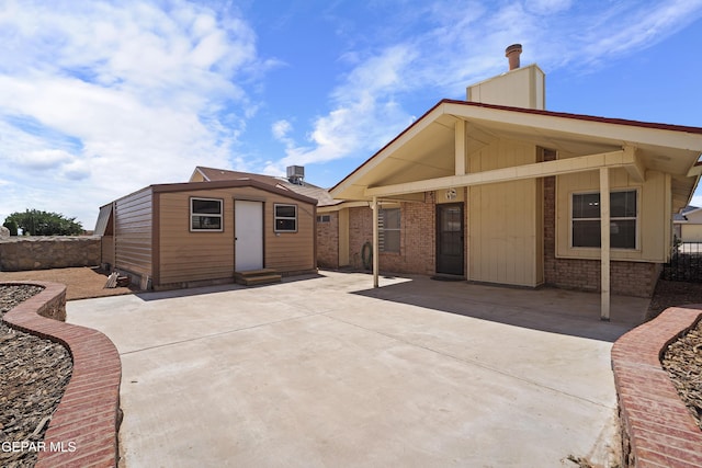 4513 Gen Maloney Cir, El Paso, TX 79924 - rear view of house with entry steps, a chimney, an outdoor structure, brick siding, and a patio area