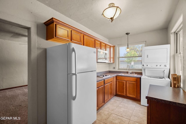 5300 Crawford Rd, Santa Teresa, NM 88008 - kitchen featuring freestanding refrigerator, stainless steel microwave, a sink, stacked washer and clothes dryer, and dark countertops