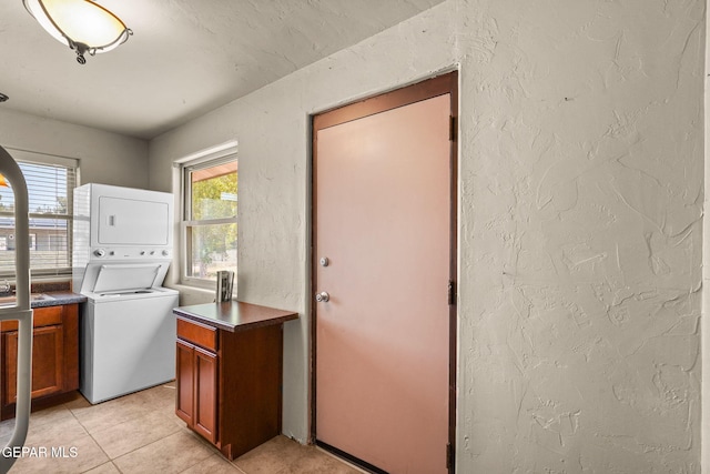 5300 Crawford Rd, Santa Teresa, NM 88008 - laundry area featuring stacked washer / drying machine, cabinet space, a textured wall, light tile patterned floors, and healthy amount of natural light