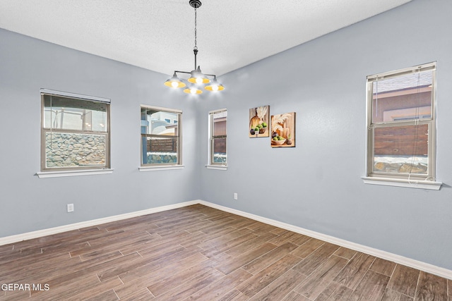 14045 Tower Point Way, El Paso, TX 79938 - unfurnished room with a chandelier, wood finished floors, baseboards, and a textured ceiling