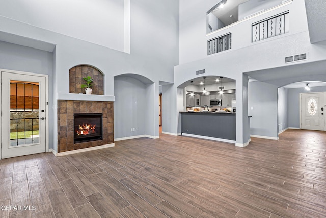 14045 Tower Point Way, El Paso, TX 79938 - unfurnished living room with healthy amount of natural light, arched walkways, dark wood-style flooring, and a high ceiling