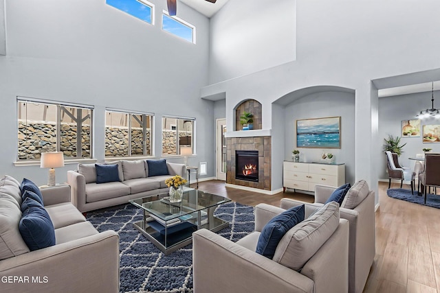 14045 Tower Point Way, El Paso, TX 79938 - living area with wood finished floors, a towering ceiling, a tile fireplace, and a ceiling fan