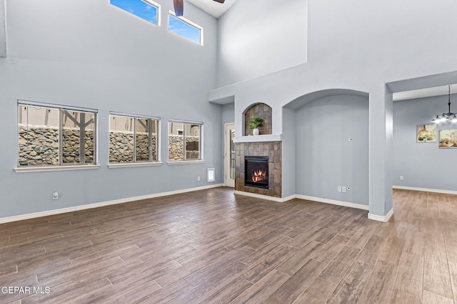 14045 Tower Point Way, El Paso, TX 79938 - unfurnished living room with a high ceiling, a ceiling fan, wood finished floors, a glass covered fireplace, and baseboards