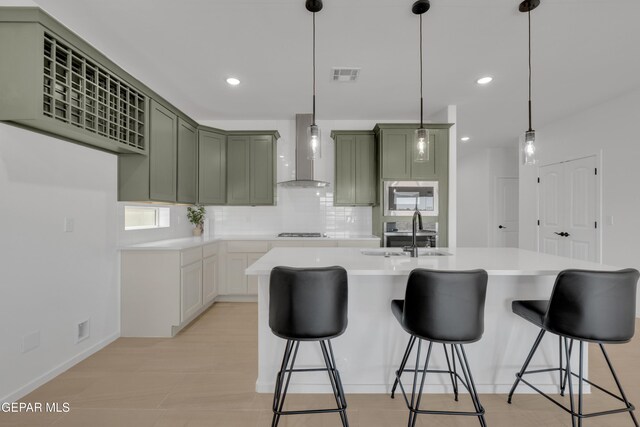 13873 Madero Ave, Horizon City, TX 79928 - kitchen with wall chimney exhaust hood, green cabinetry, stainless steel microwave, backsplash, and light countertops