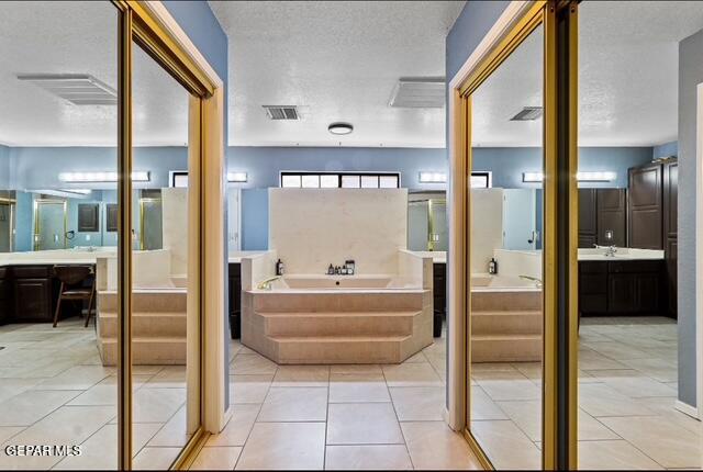 16006 Darley Dr, Horizon City, TX 79928 - bathroom with a bath, two vanities, a textured ceiling, and tile patterned floors