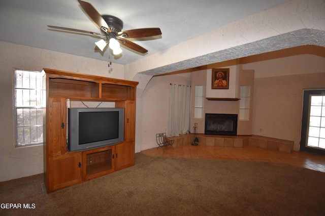 3608 Douglas Ave, El Paso, TX 79903 - unfurnished living room featuring a tiled fireplace, ceiling fan, carpet, and a textured wall