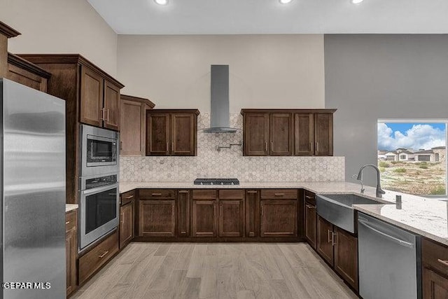 3928 Aspiration, El Paso, TX 79934 - kitchen with stainless steel appliances, wall chimney range hood, a sink, dark brown cabinetry, and backsplash