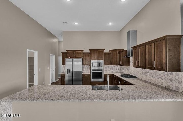 3928 Aspiration, El Paso, TX 79934 - kitchen featuring stainless steel appliances, wall chimney range hood, a sink, light stone counters, and backsplash