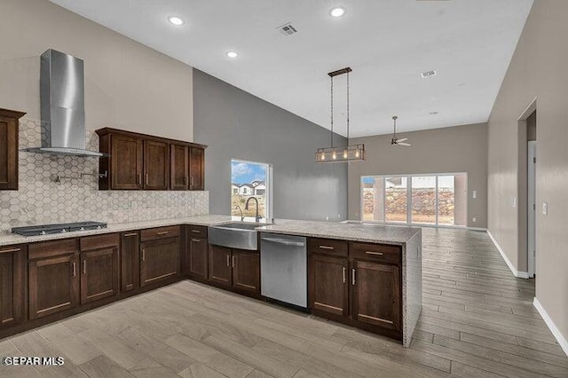 3928 Aspiration, El Paso, TX 79934 - kitchen with stainless steel appliances, wall chimney exhaust hood, a peninsula, dark brown cabinets, and tasteful backsplash
