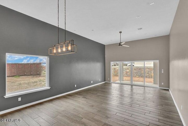 3928 Aspiration, El Paso, TX 79934 - unfurnished dining area with a towering ceiling, wood finished floors, ceiling fan, baseboards, and a chandelier