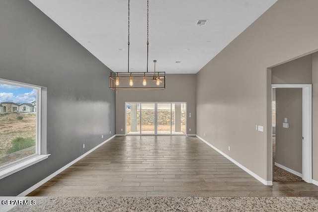 3928 Aspiration, El Paso, TX 79934 - unfurnished dining area featuring a towering ceiling, wood finished floors, and baseboards