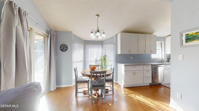 684 Abington Dr, El Paso, TX 79912 - dining space with light wood-style flooring, a chandelier, a textured ceiling, plenty of natural light, and baseboards