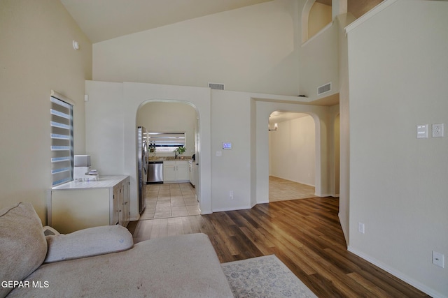 7044 Eagle Nest Ct, El Paso, TX 79934 - living room with high vaulted ceiling, arched walkways, light wood-style floors, and baseboards