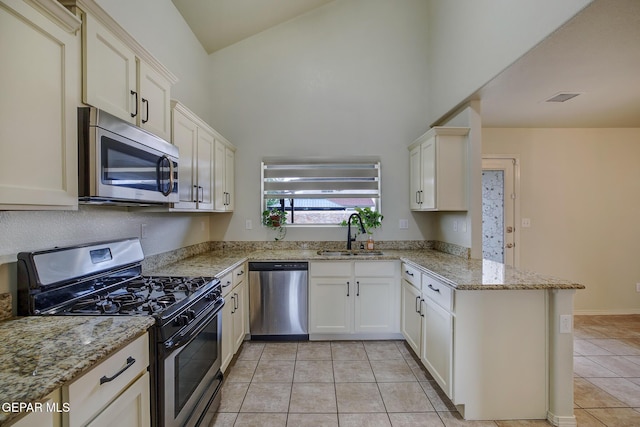 7044 Eagle Nest Ct, El Paso, TX 79934 - kitchen with appliances with stainless steel finishes, a sink, a peninsula, light tile patterned floors, and a high ceiling
