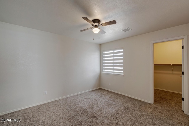 7044 Eagle Nest Ct, El Paso, TX 79934 - unfurnished bedroom featuring carpet, a walk in closet, baseboards, a ceiling fan, and a textured ceiling