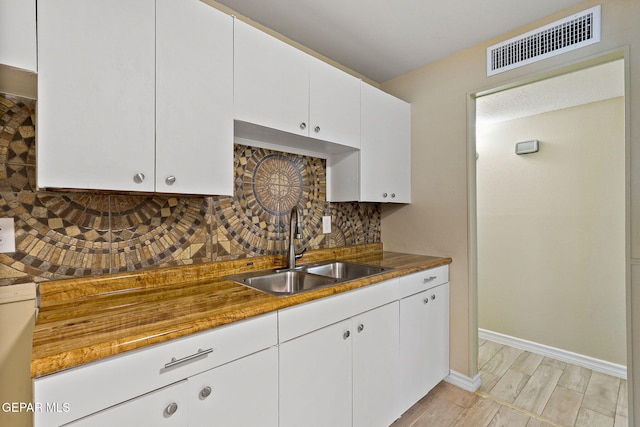 310 Kelvin Ave, El Paso, TX 79915 - kitchen with a sink, tasteful backsplash, white cabinets, baseboards, and white dishwasher