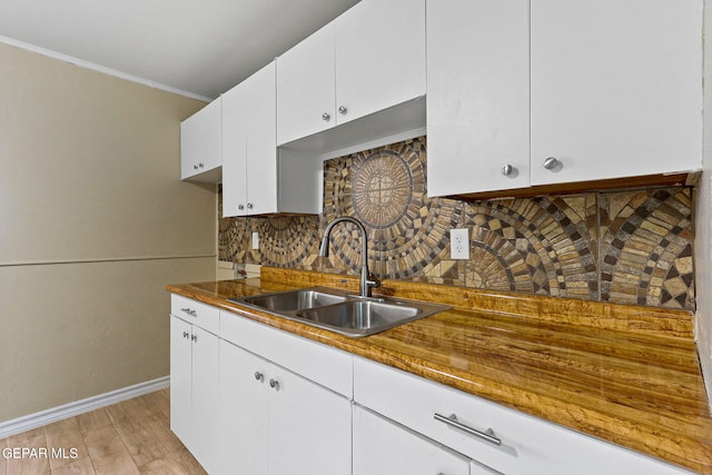 310 Kelvin Ave, El Paso, TX 79915 - kitchen featuring a sink, baseboards, backsplash, light wood-style flooring, and white cabinets