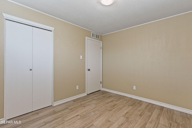 310 Kelvin Ave, El Paso, TX 79915 - unfurnished bedroom featuring light wood-type flooring, ornamental molding, a textured ceiling, baseboards, and a closet