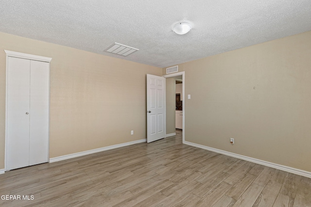 310 Kelvin Ave, El Paso, TX 79915 - unfurnished bedroom with light wood-style floors, a textured ceiling, baseboards, and a closet